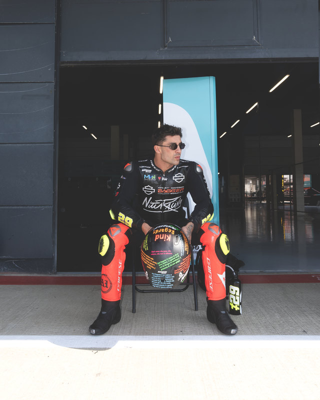 Andrea Iannone in tuta da gara, seduto davanti al box.